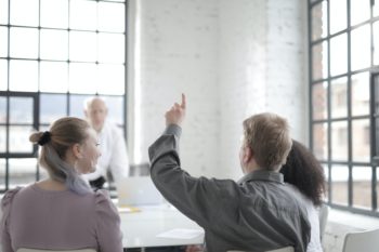 employee raising hand at meeting