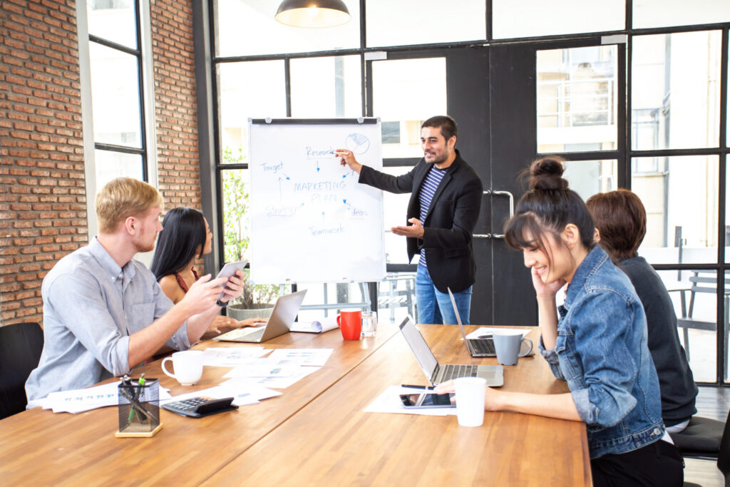 A marketing director holds a meeting in front of a board.