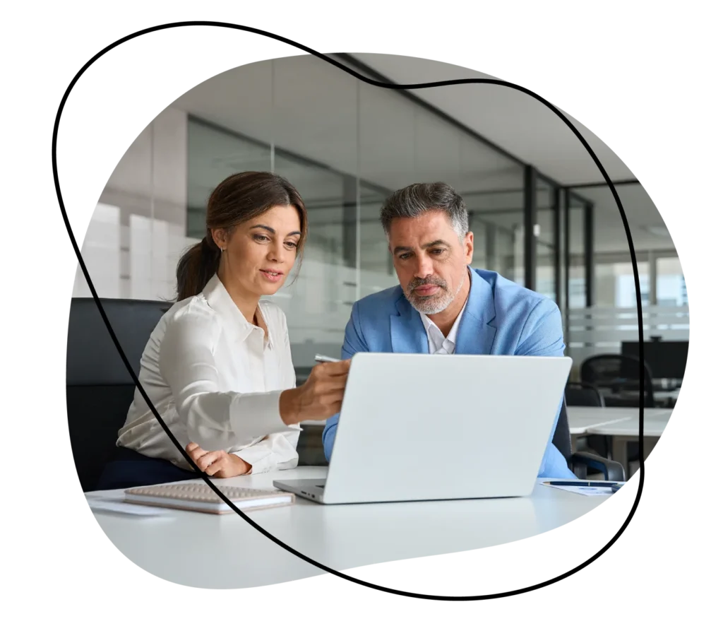 Two professionals discussing recruitment strategies on a laptop in a modern office.